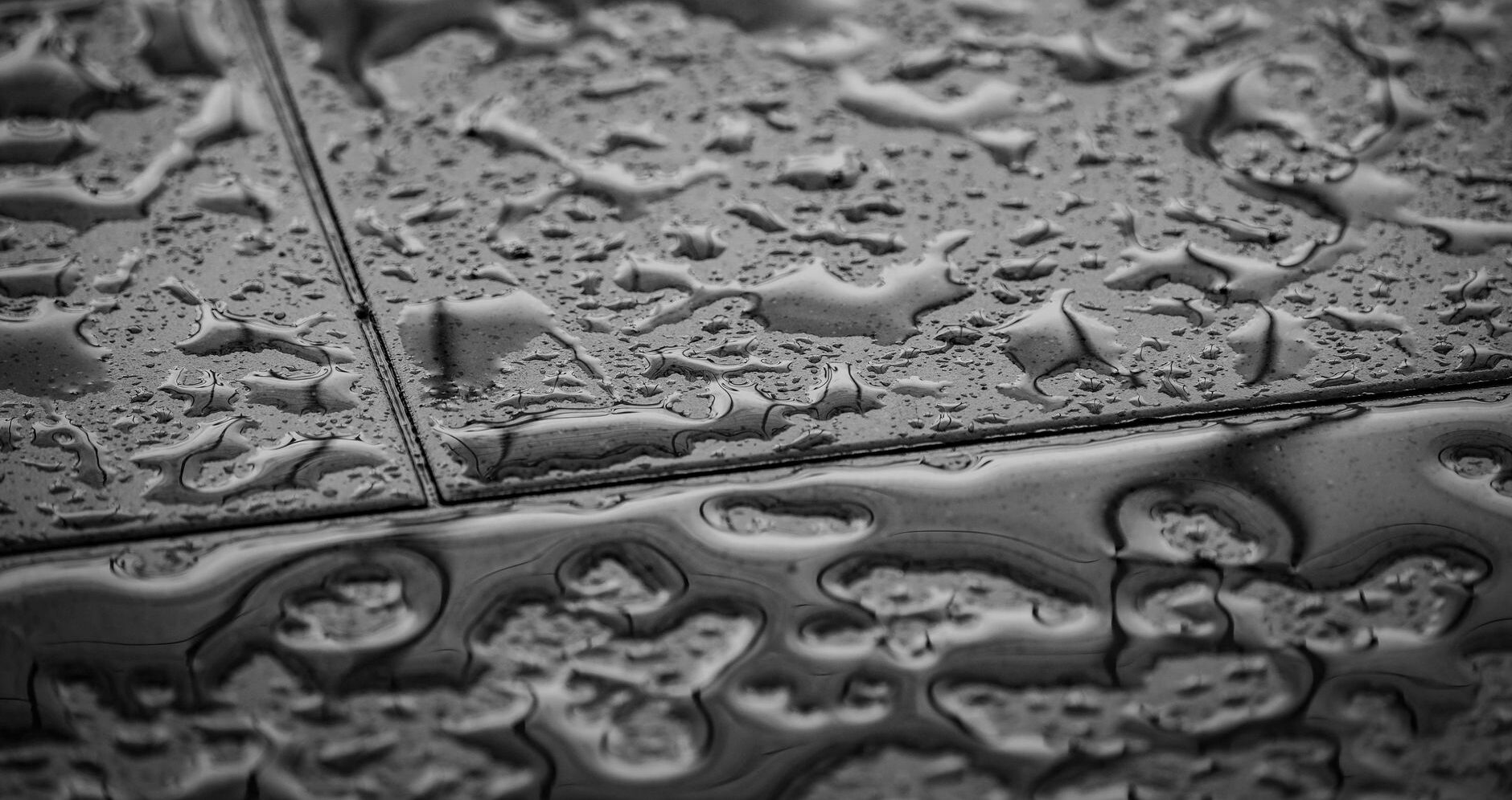 grayscale photo of water droplets on tiled floor